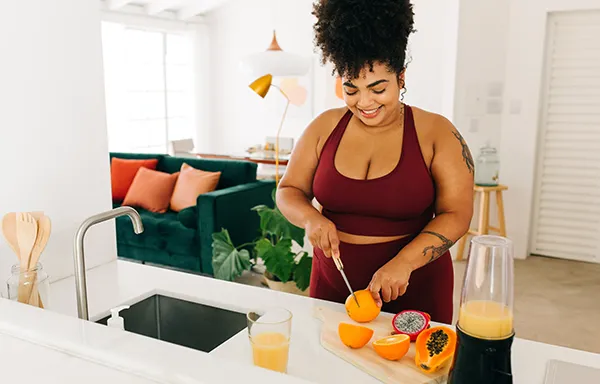 a woman cutting up fruit to make juice after a workout
