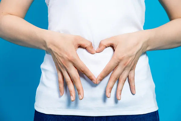 Woman making a heart with her hands on her stomach