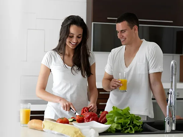 happy young couple have fun in modern kitchen indoor while preparing fresh fruits and vegetables food salad