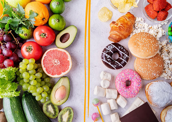 fruits and vegetables with good carbs on one side and sugary foods like donuts and candy on the other side